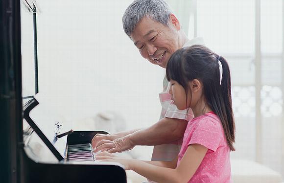 Older man teaching younger girl how to play piano.